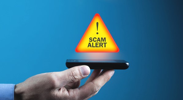 hand holding cell phone with scam alert warning displayed
